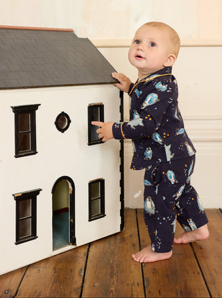 Child playing with a dollhouse on a wooden floor.